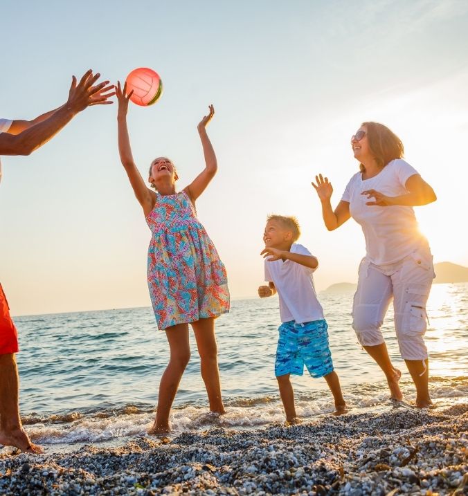 Family playing beach volleyball at sunset on the shores of La Cala